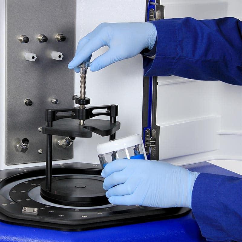 Hands in gloves adding a container into the LabRAM II for mixing